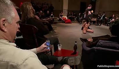 Hot ebony girl performs BDSM sexual acts in front of a large male audience