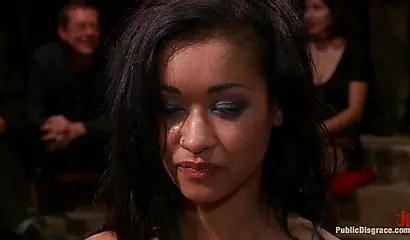 Hot ebony girl performs BDSM sexual acts in front of a large male audience