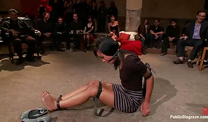 Hot ebony girl performs BDSM sexual acts in front of a large male audience