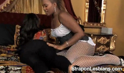 Two ebony cuties have some fun on a big bed with the help of a giant dildo